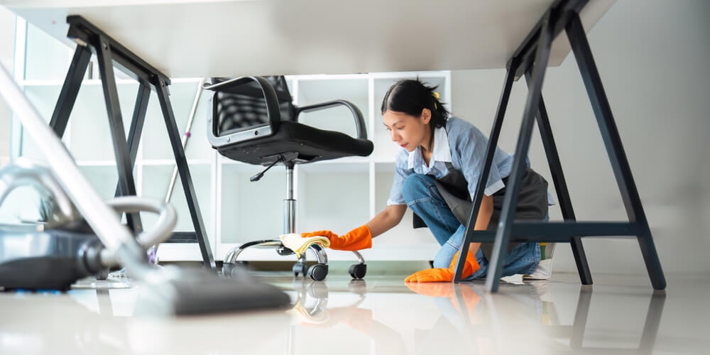 Femme asiatique nettoyant dans son bureau à la maison. Une jeune femme au ménage utilise un chiffon pour essuyer l'équipement nécessaire au travail. concept entretien ménager nettoyage.