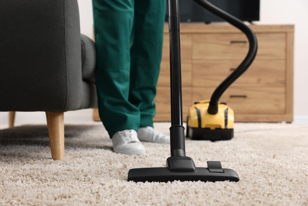 Employé d'un nettoyeur à sec qui recouvre le tapis avec l'aspirateur à l'intérieur, gros plan.