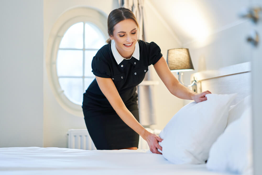 La femme de ménage fait un lit dans la chambre d'hôtel.
